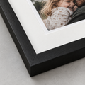 Illustrative close-up of a mounted photograph and wooden frame. The number of photographs and layout depend on the selected product.